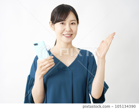 A woman holding a smartphone and pointing to the right side with her palm White background 105134390