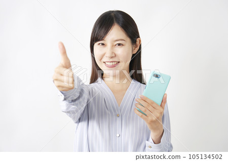A middle-aged woman holding a smartphone and giving a good sign White background 105134502