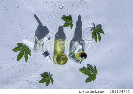 Cbd Oil Bottles, Blue water background with drops, waves and leaves of hemp, marijuana Cbd Oil Bottles, Blue water background with drops, waves and leaves of hemp, marijuana 105134765
