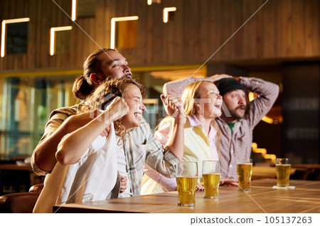 Emotive sport fans, friends, men and women sitting in cafe and watching football match translation, cheering up favourite team Emotive sport fans, friends, men and women sitting in cafe and watching football match translation, cheering up favourite team 105137263