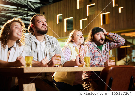 Emotive sport fans, friends, men and women sitting in cafe and watching football match translation, cheering up favourite team Emotive sport fans, friends, men and women sitting in cafe and watching football match translation, cheering up favourite team 105137264