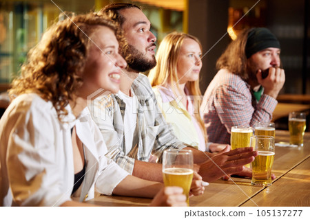 Sport fans, friends sitting at pub, bar, watching online football match translation, drinking beer, cheering up team Sport fans, friends sitting at pub, bar, watching online football match translation, drinking beer, cheering up team 105137277
