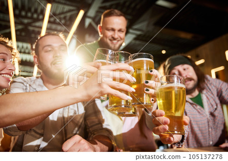 Friends meeting at bar, pub,watching football match translation, talking, cheering up favorite team. Clinking beer glasses 105137278
