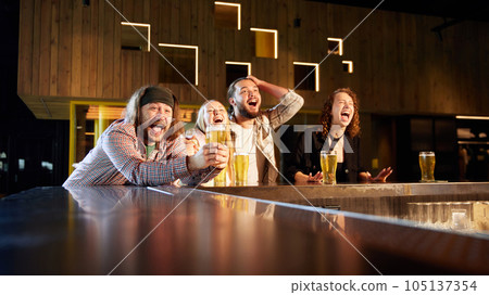 Young emotional people, friends, sport fans visiting bar, drinking beer, watching sport match translation Young emotional people, friends, sport fans visiting bar, drinking beer, watching sport match translation 105137354