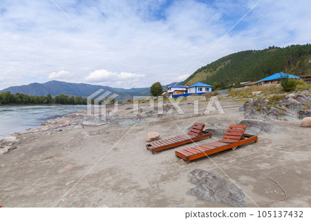Two empty wooden sun loungers stand on the Katun river coast Two empty wooden sun loungers stand on the Katun river coast 105137432