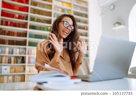 Woman with wireless headphones calling on laptop, talk by webcam sitting on modern cafe. Education. Woman with wireless headphones calling on laptop, talk by webcam sitting on modern cafe. Education. 105137785