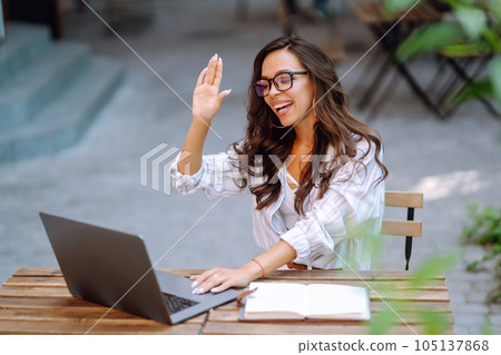 Young woman with wireless headphones calling on laptop, talk by webcam, video conference on cafe. Young woman with wireless headphones calling on laptop, talk by webcam, video conference on cafe. 105137868