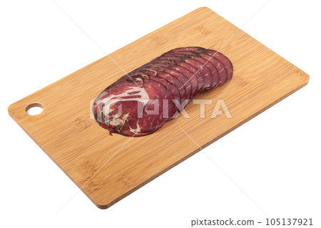 Sliced dry-cured pork neck on a cutting board on a white background. Sliced dry-cured pork neck on a cutting board on a white background. 105137921