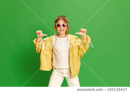 Confident child. Photo of little girl wearing stylishly, listening to music over green background. Confident child. Photo of little girl wearing stylishly, listening to music over green background. 105138427