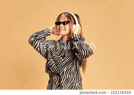 Portrait of beautiful little girl wearing glasses while listening music with earphones Portrait of beautiful little girl wearing glasses while listening music with earphones 105138439