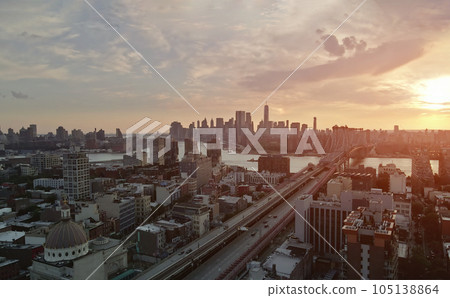 During sunset is panoramic view visible Manhattan across East River crossed by Williamsburg Bridge in New York city 105138864