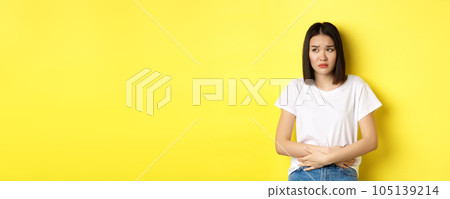 Image of asian woman feeling sick, having painful cramps, holding hands on belly and frowning from pain, discomfort during menstrual period, standing over yellow background Image of asian woman feeling sick, having painful cramps, holding hands on belly and frowning from pain, discomfort during menstrual period, standing over yellow background 105139214