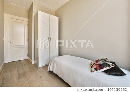 a bedroom with white walls and wood flooring the room has a bed, two wardrobes on either side 105139362