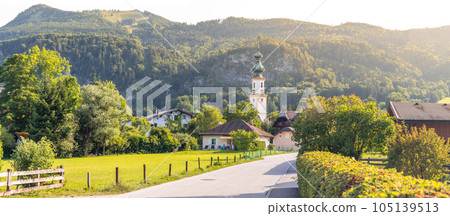 landscape with road and church tower in the village of Sankt Gilgen, Zwolferhorn mountains in background, Alps, Austria 105139513