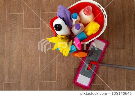 Various household cleaning detergents and bottles in a plastic bucket on the floor 105140645