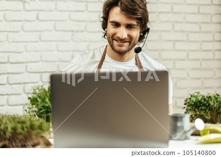 Handsome bearded man sells plant sprouts and seedlings online using laptop 105140800