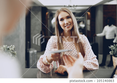 Blonde woman hotel guest checking-in at front desk in hotel 105140863