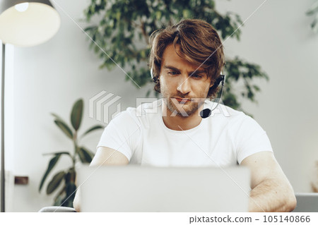 Young man businessman with headset working on laptop from home 105140866