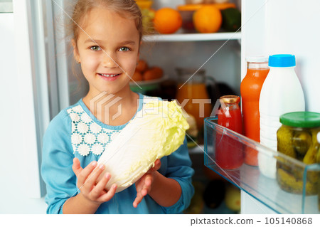 Little girl standing in front of a fridge and choosing food Little girl standing in front of a fridge and choosing food 105140868