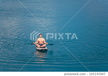 man on paddleboard in the middle of the lake man on paddleboard in the middle of the lake 105141007