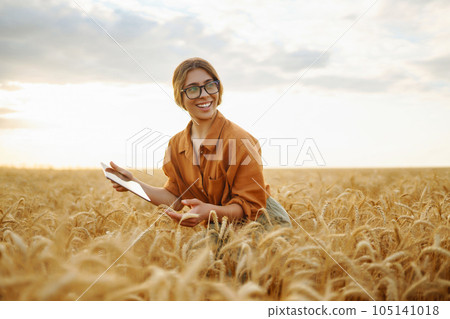 Farmer- woman on wheat field with tablet in his hands. Smart farm. Agriculture, gardening concept. 105141018