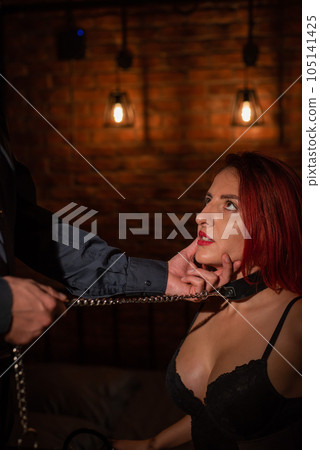 BDSM. A man holds a kneeling woman by the chin. BDSM. A man holds a kneeling woman by the chin. 105141425