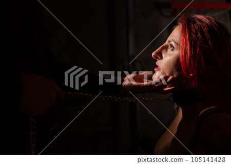 BDSM. A man holds a kneeling woman by the chin.  105141428