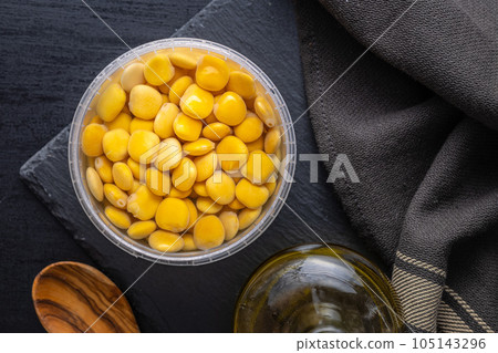 Lupini beans in brine. Pickled lupin in bowl on black table. Top view. Lupini beans in brine. Pickled lupin in bowl on black table. Top view. 105143296