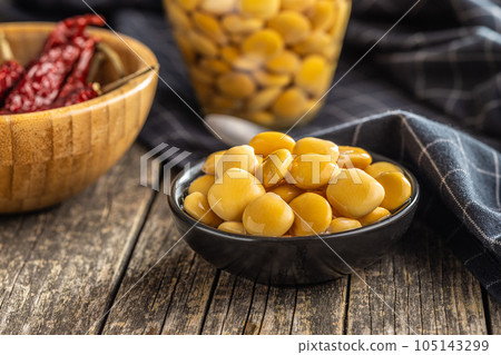 Lupini beans in brine. Pickled lupin in bowl on wooden table. 105143299
