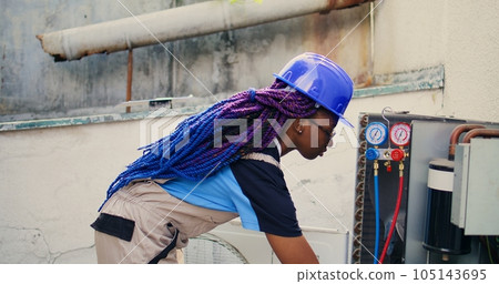 Close up portrait of smiling african american electrician mounting manometer used for checking condenser freon tank in need of repairing. Engineer using manifold gauges to check refrigerant levels Close up portrait of smiling african american electrician mounting manometer used for checking condenser freon tank in need of repairing. Engineer using manifold gauges to check refrigerant levels 105143695