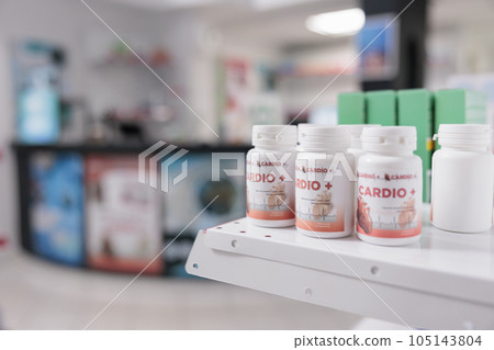 Selective focus of pills packages standing on shelves in empty pharmacy store, prepared for clients to buy. Drugstore space filled with pharmaceutical products and supplement boxes Selective focus of pills packages standing on shelves in empty pharmacy store, prepared for clients to buy. Drugstore space filled with pharmaceutical products and supplement boxes 105143804