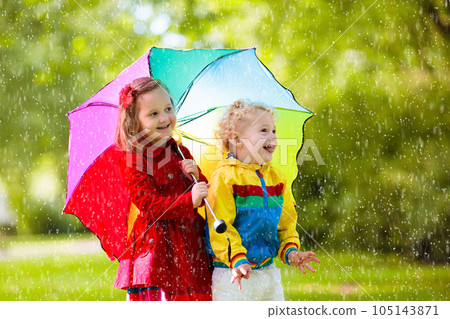 Kids playing in the rain under colorful umbrella 105143871