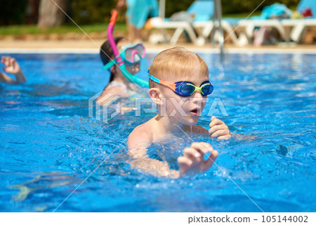 Young boy kid child eight years old splashing in swimming pool having fun leisure activity. Boy happy swimming in a pool. Activities on the pool, children swimming and playing in water, happiness and Young boy kid child eight years old splashing in swimming pool having fun leisure activity. Boy happy swimming in a pool. Activities on the pool, children swimming and playing in water, happiness and 105144002