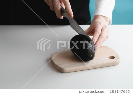 Woman's hand cutting avocado Woman's hand cutting avocado 105147665
