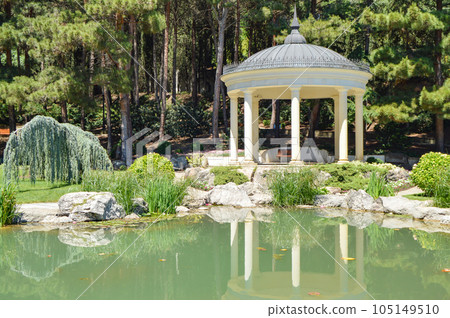Picturesque view of the round gazebo by the fish pond, sunny summer day Picturesque view of the round gazebo by the fish pond, sunny summer day 105149510