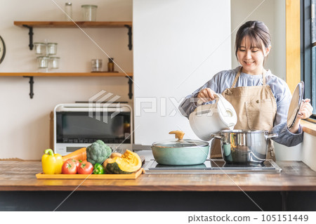 圍裙的亞裔婦女在廚房的電水壺裡放熱水 105151449