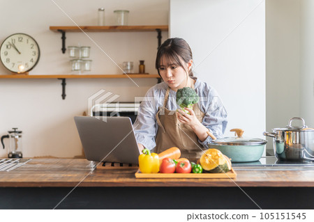亞洲家庭主婦/女管家使用筆記本電腦尋找家庭廚房烹飪的食譜和營養素 亞洲家庭主婦/女管家使用筆記本電腦尋找家庭廚房烹飪的食譜和營養素 105151545