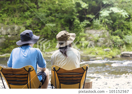 A young man and a woman sitting side by side on a chair and looking at the river A young man and a woman sitting side by side on a chair and looking at the river 105152567