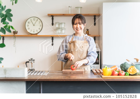 Female standing in the kitchen (cutting vegetables) 105152828