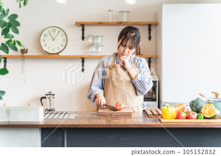 Asian woman who is not good at cooking in the kitchen and is worried about cutting tomatoes Asian woman who is not good at cooking in the kitchen and is worried about cutting tomatoes 105152832