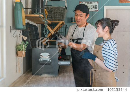 一個男人在解釋汽車維修的工具和工具,例如在他家的車庫裡更換輪胎,一個女人正在學習(車間) 一個男人在解釋汽車維修的工具和工具,例如在他家的車庫裡更換輪胎,一個女人正在學習(車間) 105153544