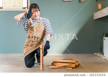 Men and women who use an ax to chop firewood in a house garage/storeroom (DIY/workshop/experience class) Men and women who use an ax to chop firewood in a house garage/storeroom (DIY/workshop/experience class) 105153554
