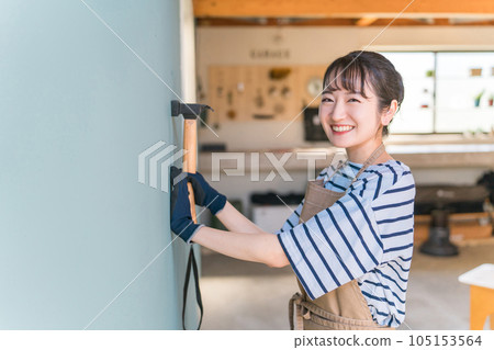 Japanese woman driving a nail in the garage (renovation/DIY) Japanese woman driving a nail in the garage (renovation/DIY) 105153564