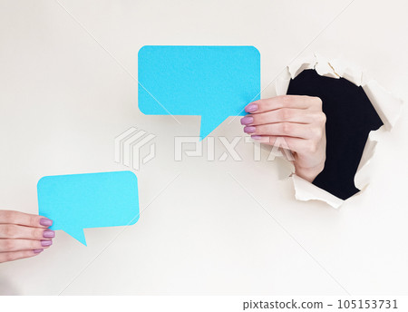 Dialogue icon. Blank speech bubble. Female hands inside breakthrough paper hole showing blue message mockup on white torn background with empty space. Dialogue icon. Blank speech bubble. Female hands inside breakthrough paper hole showing blue message mockup on white torn background with empty space. 105153731