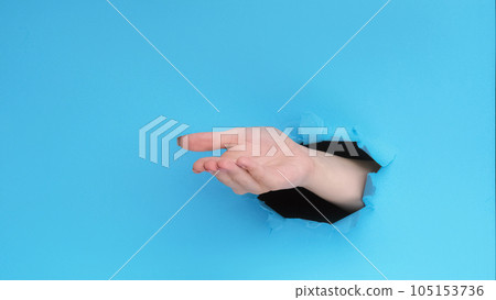Give gesture. Pay money. Female hand open palm inside breakthrough hole on blue ripped paper wall advertising background with empty space. 105153736