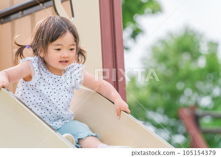 Child (girl) playing on the slide in the park 105154379