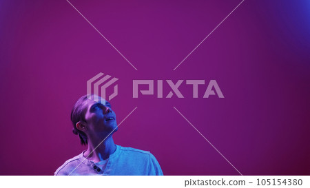 Surprised face. Neon light portrait. Special offer. Blue purple color impressed smiling guy reading invisible text on dark futuristic copy space commercial background. 105154380