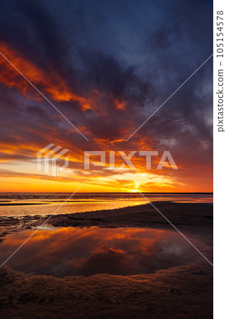sunset sky with reflections in water, sunlight and colored orange clouds. sunset sky with reflections in water, sunlight and colored orange clouds. 105154578