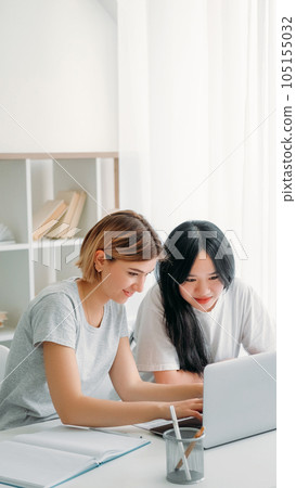 Studying teamwork. Learning cooperation. Homework together. Two happy young girls typing on laptop browsing internet for school research project at home workplace. Studying teamwork. Learning cooperation. Homework together. Two happy young girls typing on laptop browsing internet for school research project at home workplace. 105155032