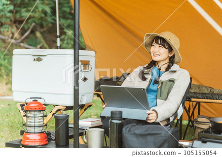 A young female camper camping solo at a campsite (reading/reading a book) 105155054
